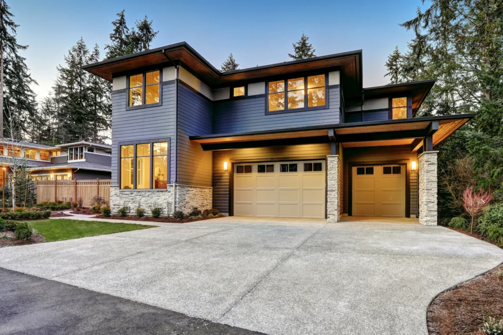 Dark gray house with bright yellow lights and beige garages in Excelsior