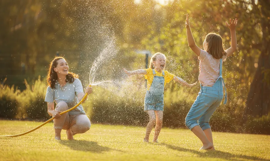 Family playing outside with a hose together in Blaine