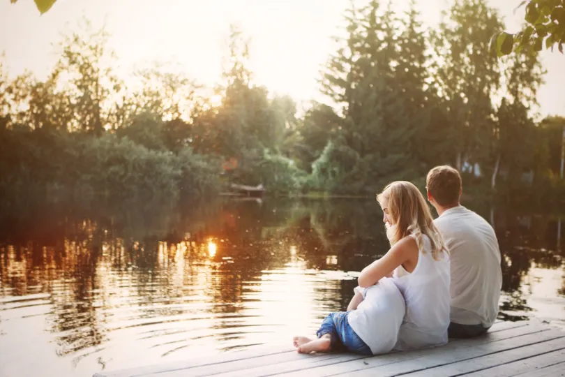 A family of homeowners sitting by a lake with a sunset in Brainerd
