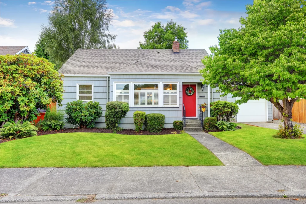 Blue house with a dark gray roof and a red door in Rogers