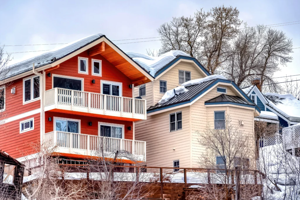 Two duplexes next to each other in the winter time with snow on their roofs