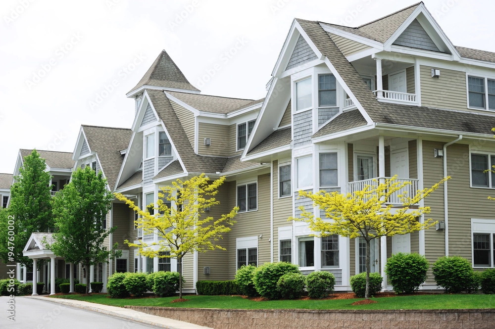 White and tan condos with tall peaked roofs with yellow trees below them