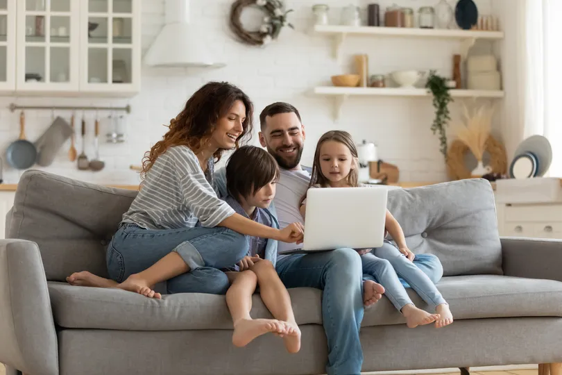 Happy young homeowners enjoy time with family on couch