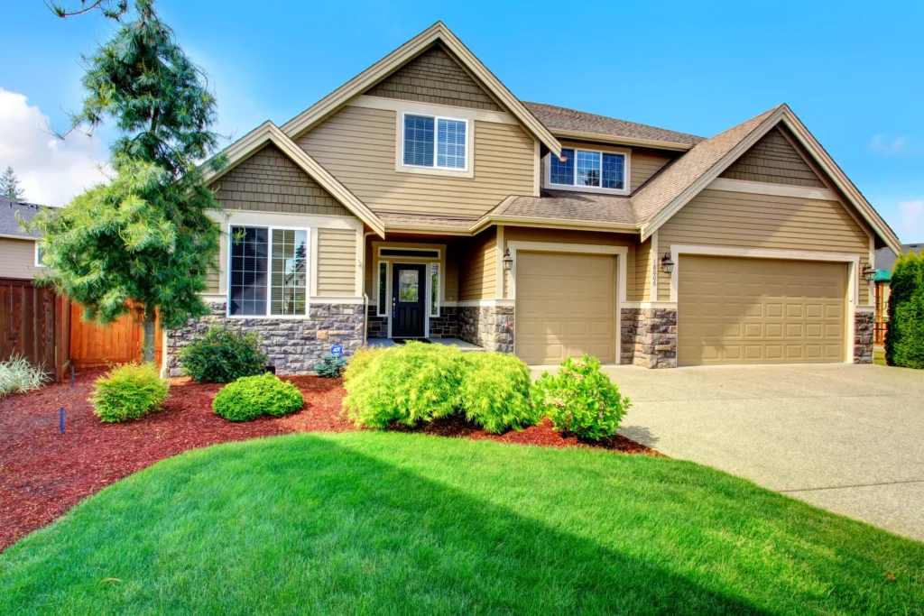 tan house with a brown roof and nice landscaping in St Cloud