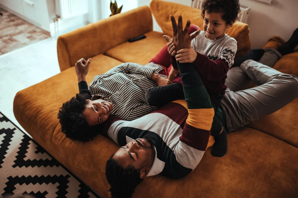 Happy younger family living in east bethel play in living room on couch