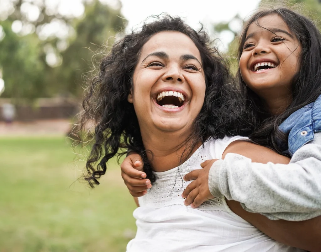 mom and daughter laughing in front yard of wayzata home