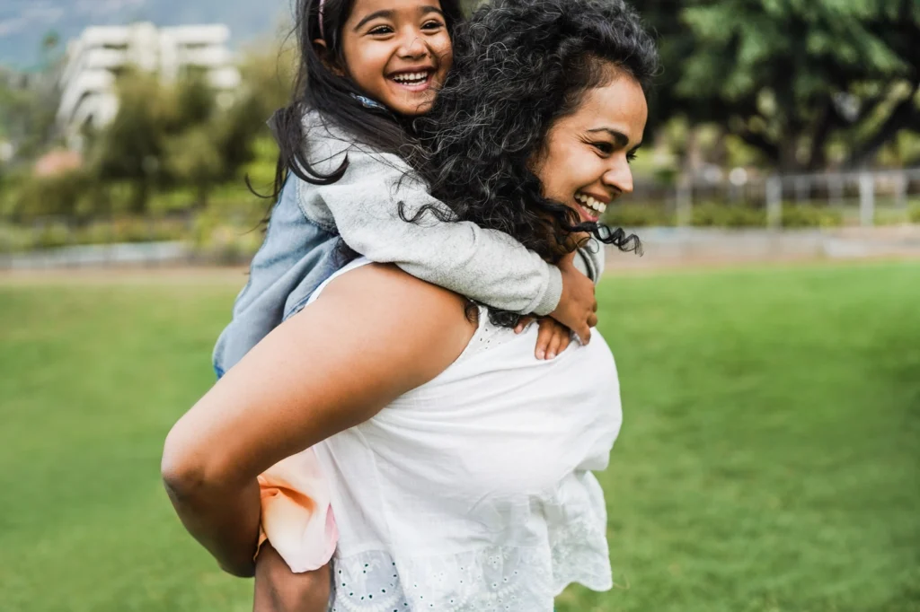 happy mother and daughter playing outside in the yard of their zimmerman home