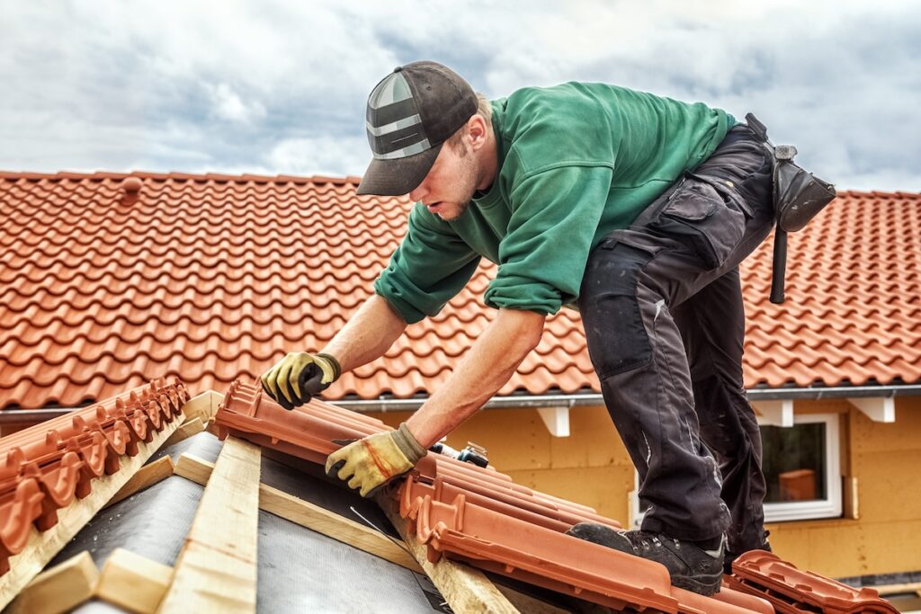 Roofer installing orange-toned roof shingles