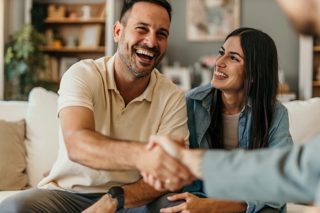 Young couple shaking hands with contractor and smiling