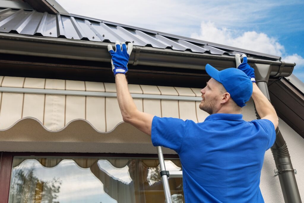 employee installing roof gutter system