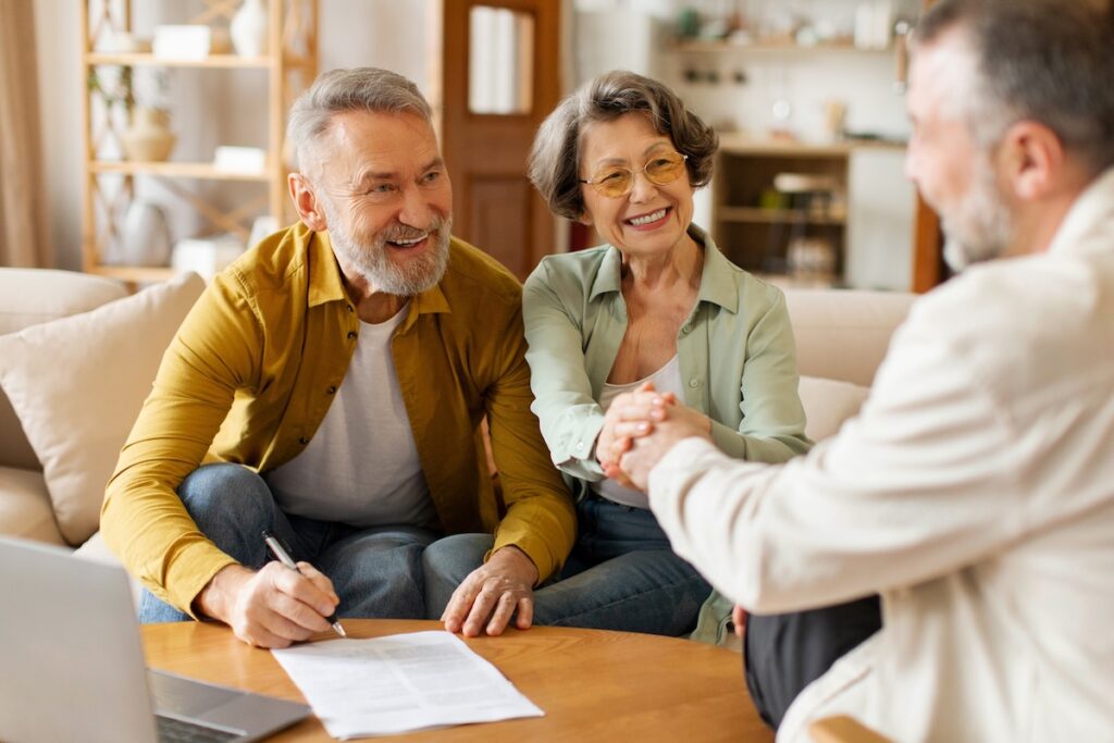 Older couple smiling and shaking hands with company representative