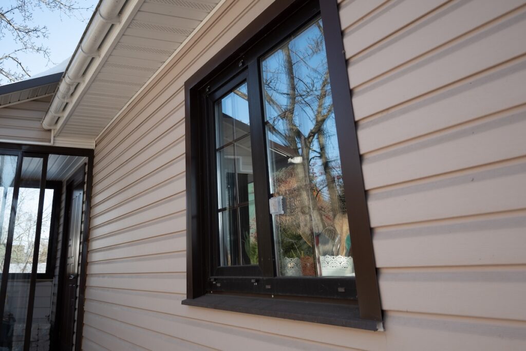 Window on wall decorated vinyl siding with reflections on it