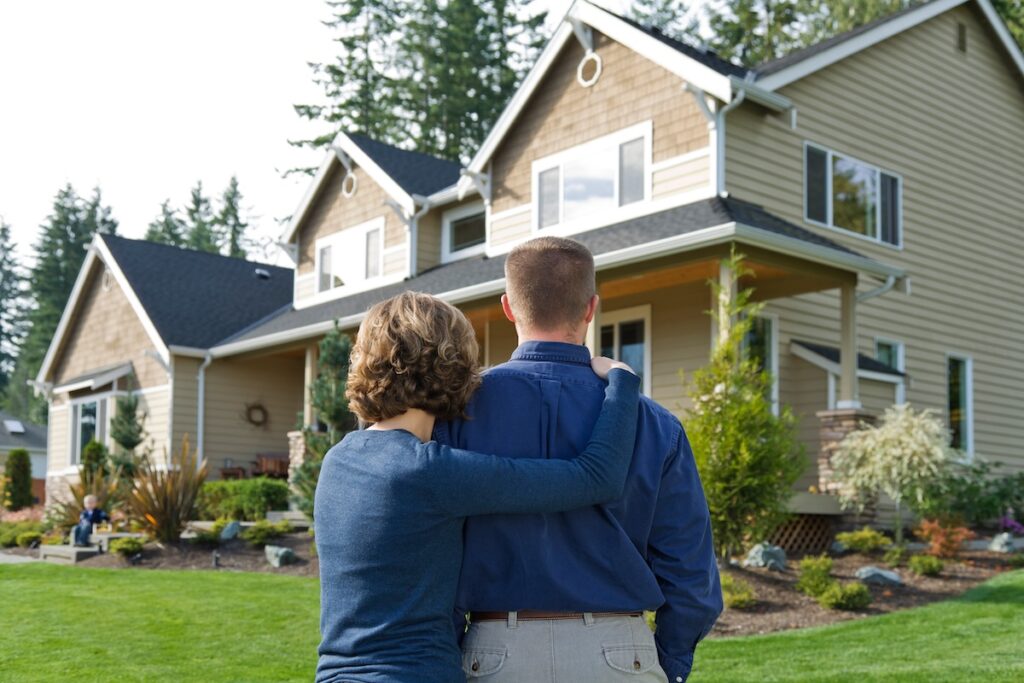 Couple looking at their house from the front yard