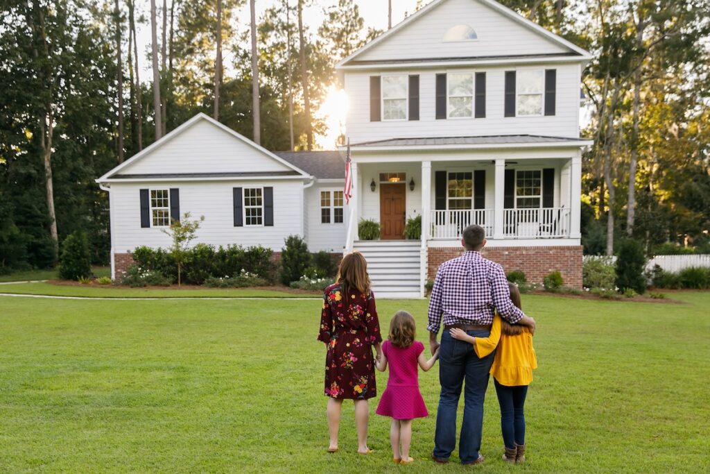 Family of four looking a their large home