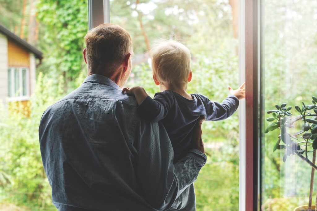grandfather taking care and spending time together with grandson at home. looking through the window