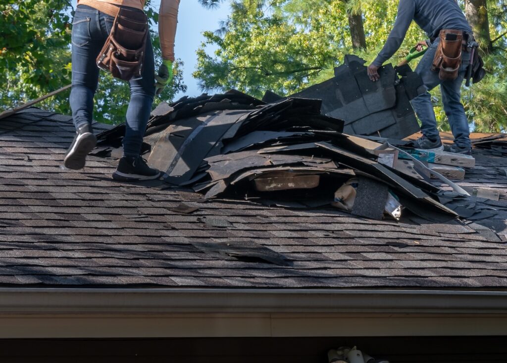 two men pulling off damage roofing