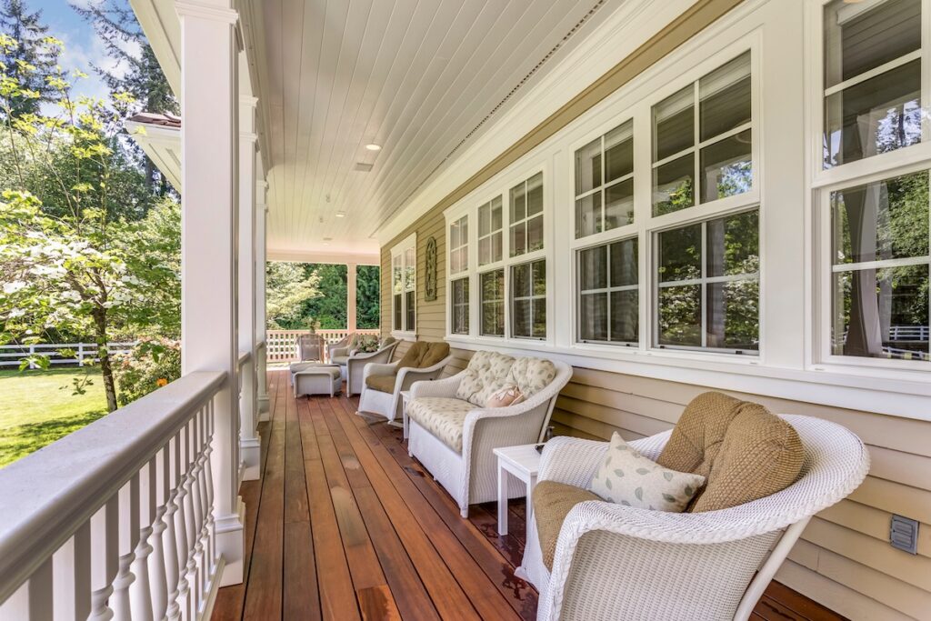 Exterior view of a large country residence with wrap-around deck and cozy sitting area.