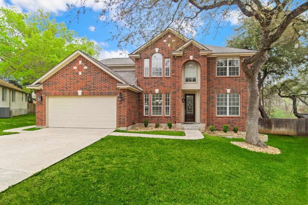 a red brick home with a green lawn and gray roof