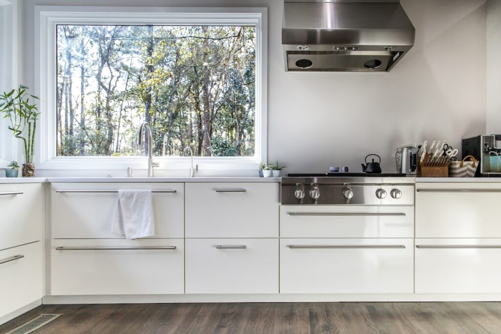 spacious large modern white kitchen recently updated with high end appliances, wood floors, picture windows, white cabinets and wood beams and a great view of the backyard